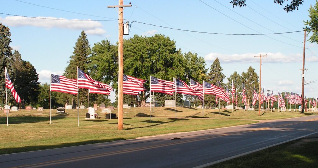 A cemetery's street in Arcadia, Nebraska lined with American flags.